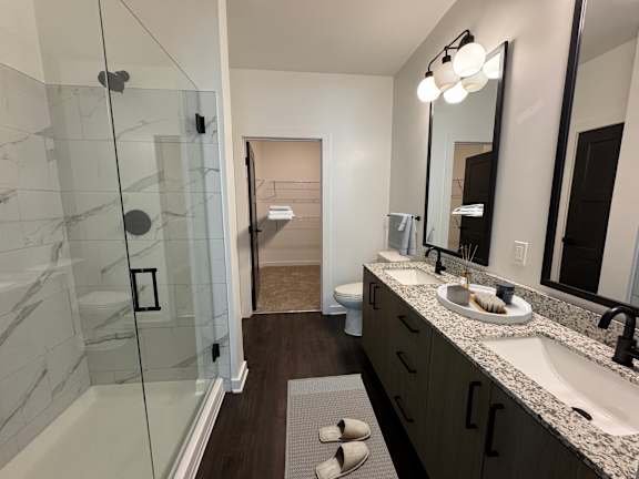 A bathroom with a glass shower stall, marble countertops, and a large mirror.