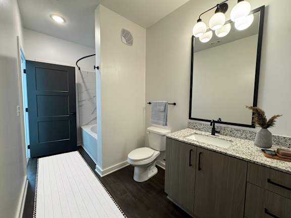 A bathroom with a toilet, sink, and mirror.