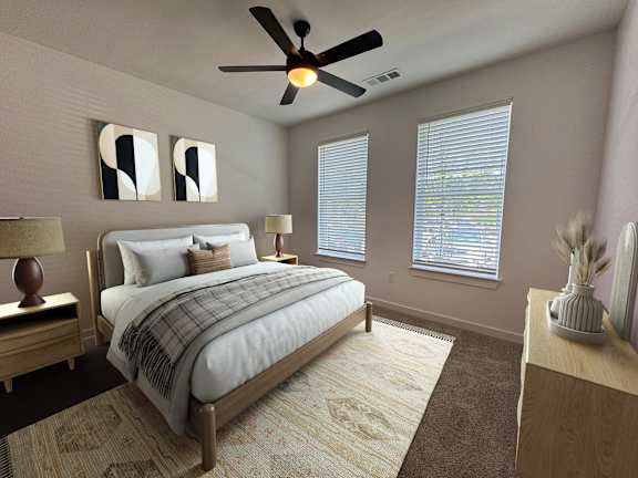 A bedroom with a bed, a ceiling fan, and two lamps.