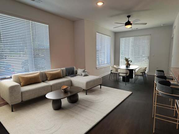 A living room with a beige couch, a coffee table, and a dining table with chairs.