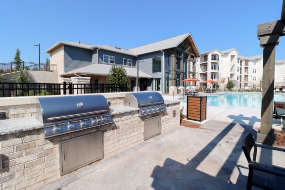 two bbq grills next to a pool with apartments in the background at The Crest at Acworth, Georgia, 30102