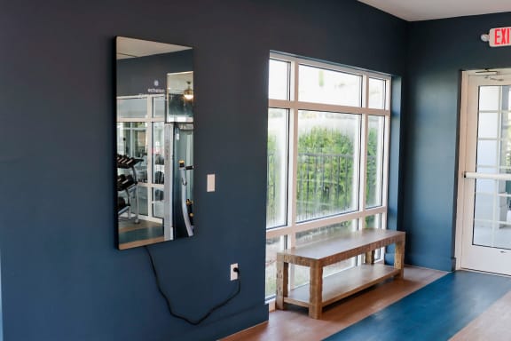 a bench in front of a window with a mirror on the wall at The Crest at Naples, Naples, FL, 34113