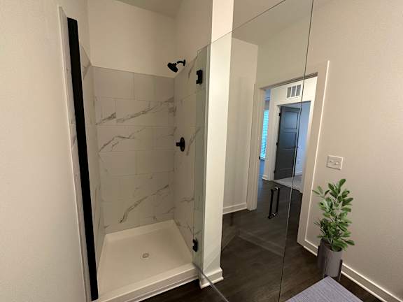 A bathroom with a marble shower and a glass door.