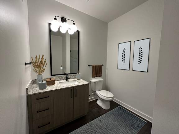 A bathroom with a toilet, sink, and mirror.