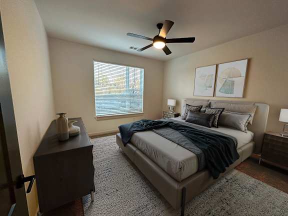 A bedroom with a bed, nightstand, and a ceiling fan.