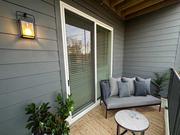 A small balcony with a grey couch and a table.