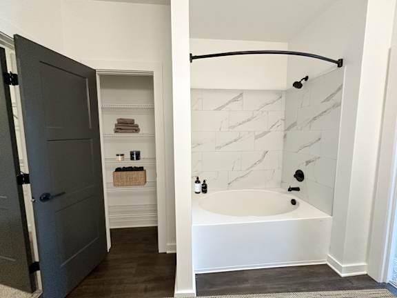 A white bathroom with a tub and a door.