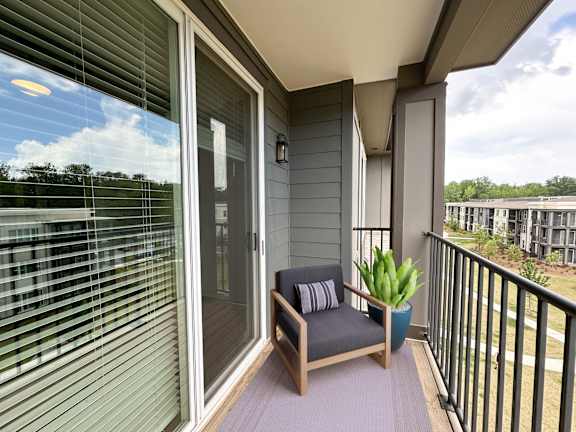 A balcony with a chair and a potted plant.