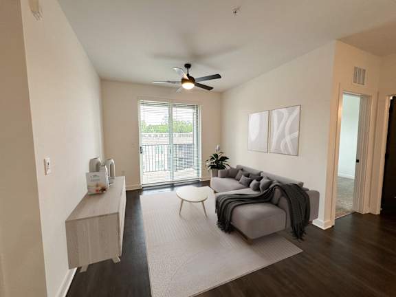A living room with a grey couch and a ceiling fan.