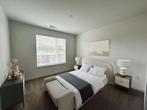 A bedroom with a large bed and a nightstand with a lamp.