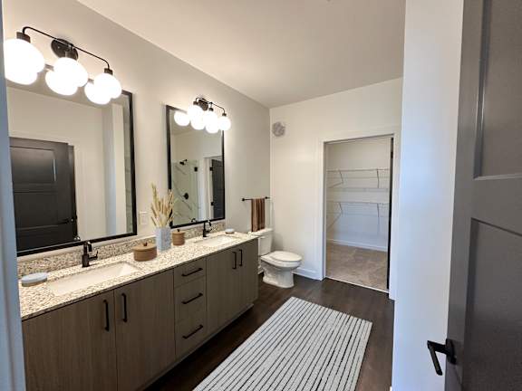 A bathroom with a vanity, toilet, and a mirror.