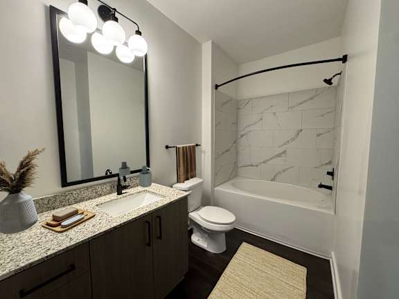 A bathroom with a marble shower and a white toilet.