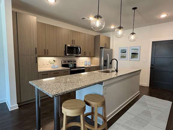 A kitchen with a granite countertop and wooden stools.