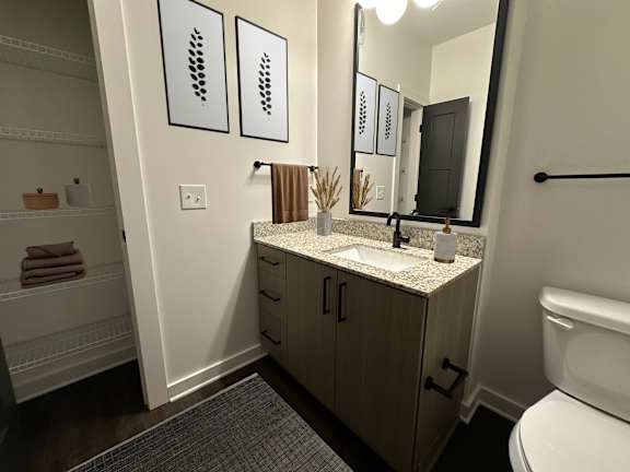 A bathroom with a toilet, sink, and mirror.