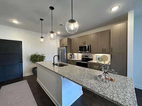 A modern kitchen with a granite countertop and pendant lights.