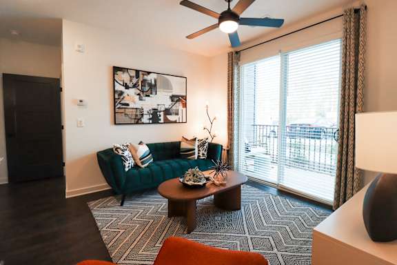 A living room with a green couch, a coffee table, and a ceiling fan.