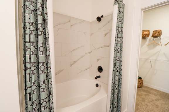 A white bathtub with a green patterned shower curtain.