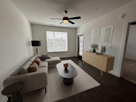 A living room with a grey couch, a coffee table, and a ceiling fan.
