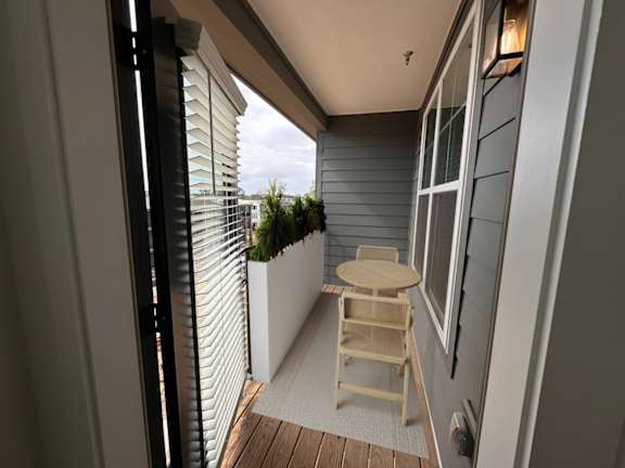 A balcony with a wooden chair and table.