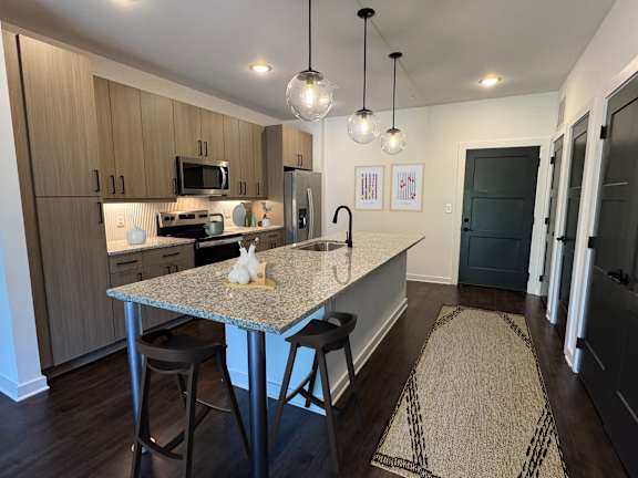 A kitchen with a granite countertop and bar stools.