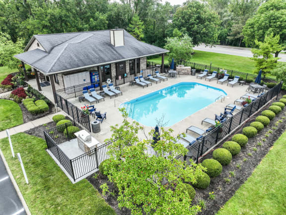 an aerial view of a resort style swimming pool with lounge chairs and a clubhouse in the background