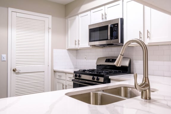 a kitchen with white cabinets and a stainless steel sink