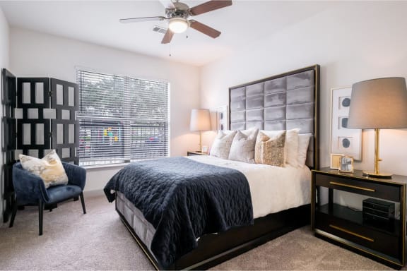 a spacious bedroom with a ceiling fan and expansive windows at The Core apartments in Houston, TX