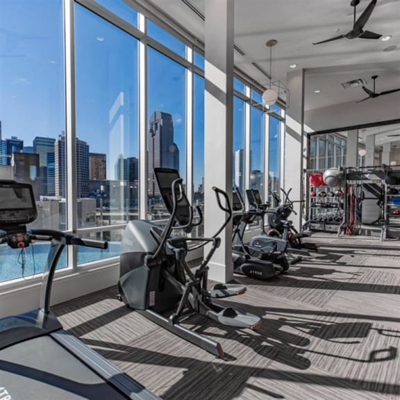 fitness center with a skyline view of Dallas at The Gabriella apartments