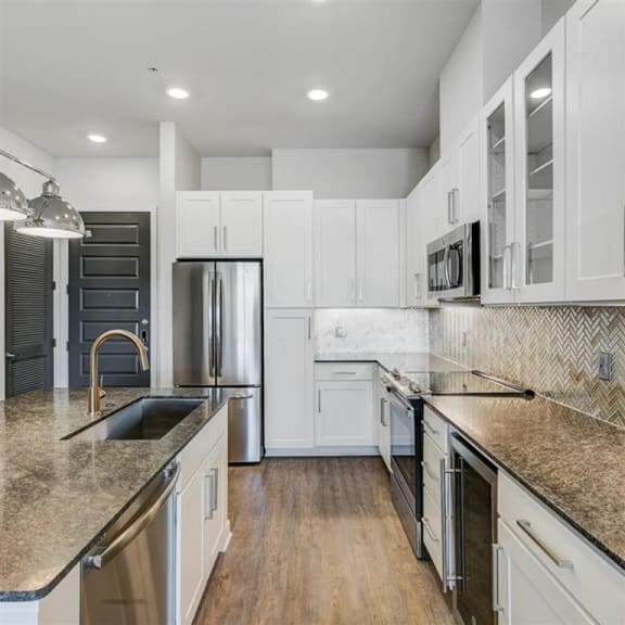 a kitchen with white cabinets and granite countertops at The Gabriella apartments