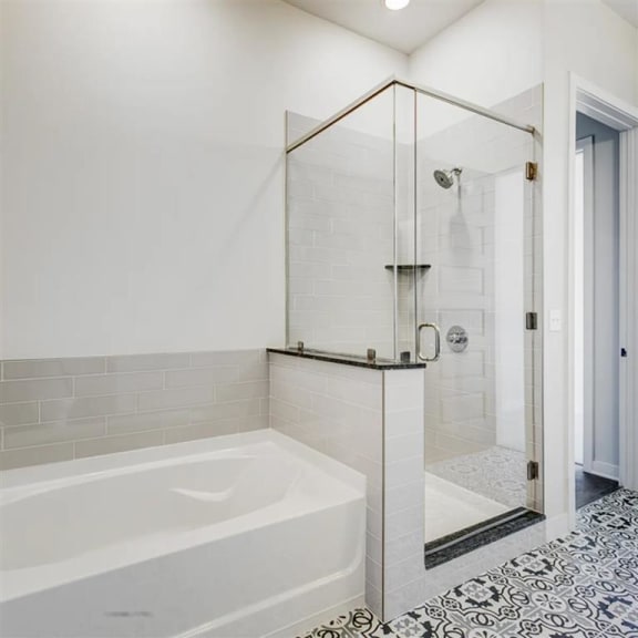 bathroom with a soaking tub and glass framed shower at The Gabriella apartments