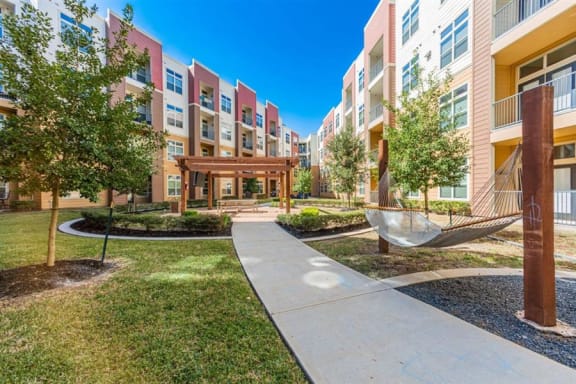 lush landscaping, hammock and walkway at Aspire at 610 apartments