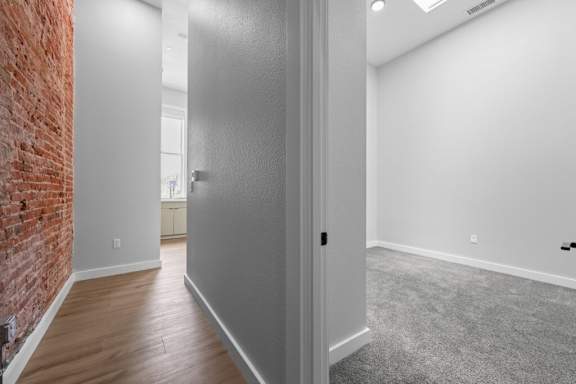 A room with a grey door and a brick wall on the left side at The Avenue Lofts Golden Apartments, Golden, CO, 80401