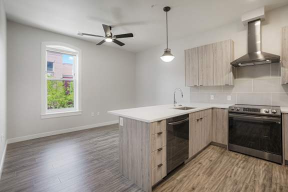 A kitchen with a stove top oven and a fan at The Avenue Lofts Golden Apartments, Golden, Colorado