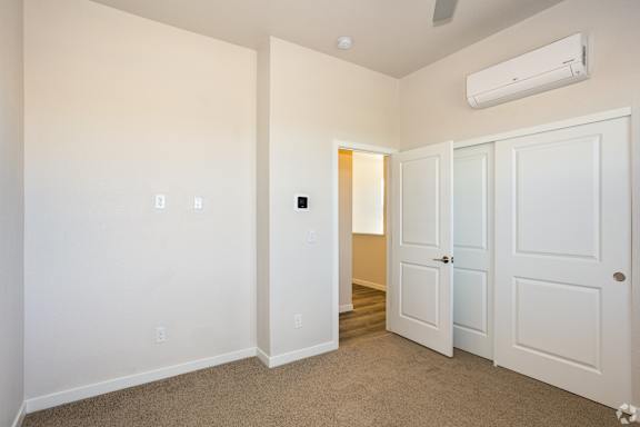 Bedroom with carpeted floor, and a wall-mounted air conditioner at Brownstones at Palisade Park, CO, 80023.
