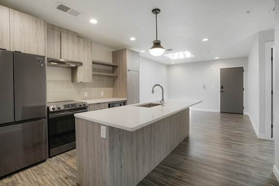 A modern kitchen with a stainless steel refrigerator and a wooden island at The Avenue Lofts Golden Apartments, Colorado, 80401