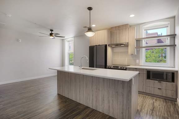 A modern kitchen with a wooden floor and a black refrigerator at The Avenue Lofts Golden Apartments, Colorado, 80401