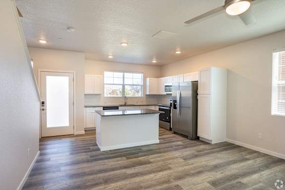 A kitchen with a refrigerator, sink, and cabinets.