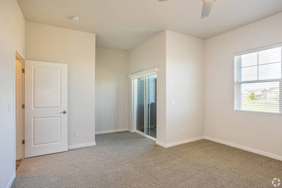 A room with a door, a window, and a ceiling fan.