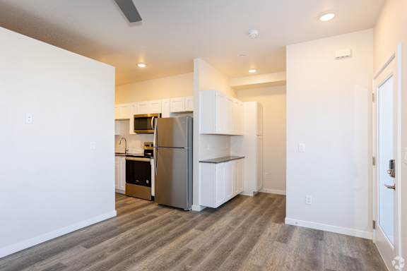 Kitchen with white cabinets, refrigerator and stove top oven at Brownstones at Palisade Park, Broomfield.
