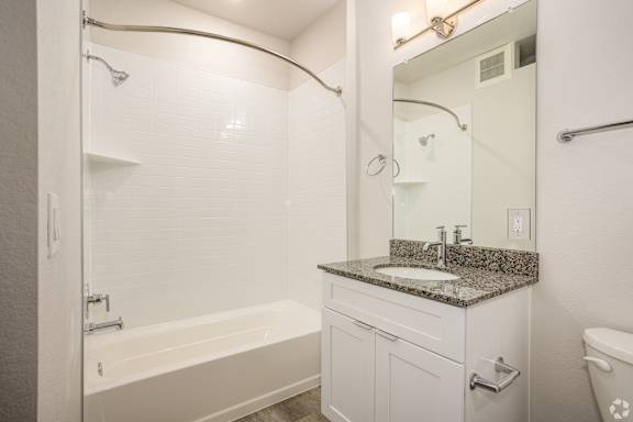 A white bathroom with a tub, sink, mirror and shower at Brownstones at Palisade Park, Broomfield,  Colorado.