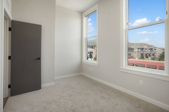 A room with a grey door and a window overlooking a residential area at The Avenue Lofts Golden Apartments, Colorado