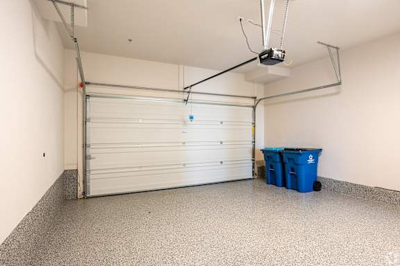 A garage with a white door and a blue bin on the floor.