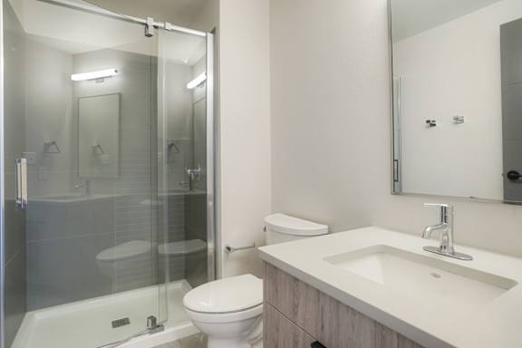 A white toilet sits next to a sink in a bathroom at The Avenue Lofts Golden Apartments, Golden
