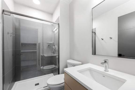 A modern bathroom with a walk-in shower and a white sink at The Avenue Lofts Golden Apartments, Golden