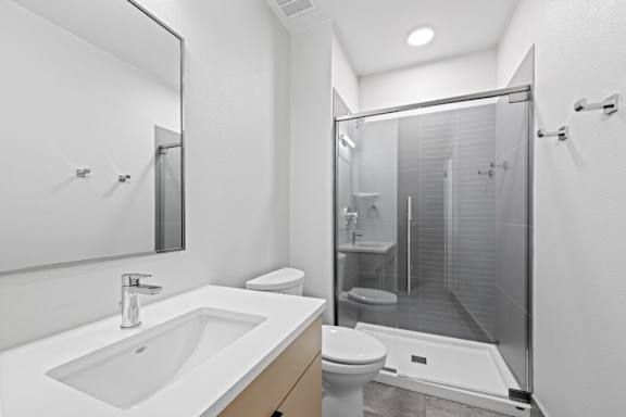 A modern bathroom with a white sink and a walk-in shower at The Avenue Lofts Golden Apartments, Golden, Colorado