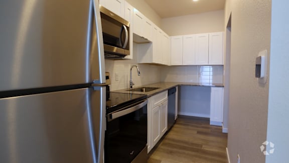 A kitchen with a stainless steel refrigerator and white cabinets.