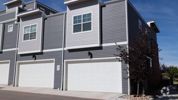 A modern two-story house with grey siding and white garage doors.