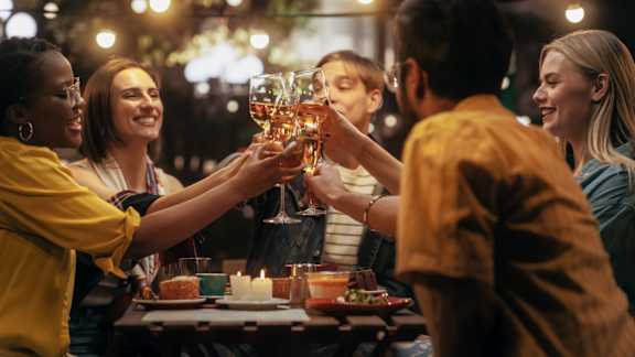 A group of people toasting with glasses of wine at a dinner table at The Avenue Lofts Golden Apartments, Golden 80401