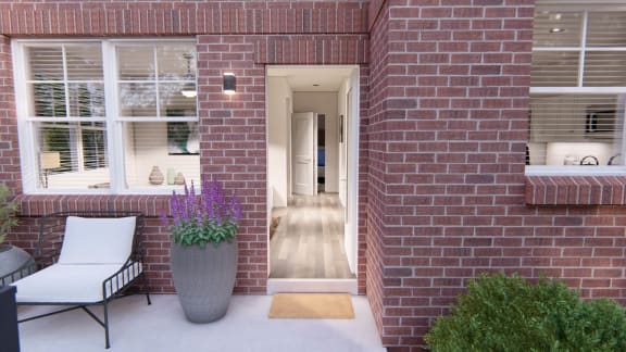 a red brick house with a porch and a large gray planter with purple flowers at Brownstones at Palisade Park Townhomes, Broomfield