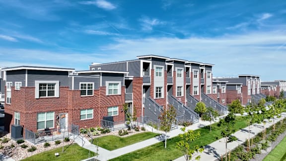 A row of red brick houses with green lawns in front.